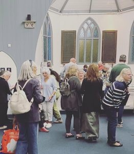 Visitors gathered inside the Tin Tabernacle at the hART 2023 exhibition in Hythe, Kent.