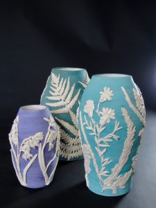 Botanical ceramic vases by Kent artist Alison Proctor, featuring raised white flowers and foliage on blue and turquoise pottery.