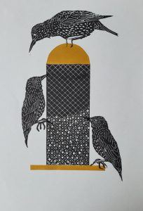 Linoprint by Beverley Johnson featuring three black birds gathered around a patterned bird feeder with ochre details.