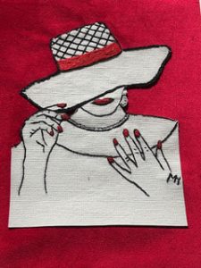 Embroidered textile portrait by Marie-Hélène Hunter showing an elegant woman in a wide-brimmed red and white hat with red nails.