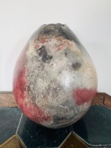 Raku ceramic vessel by Penny Graham with a rounded organic form and mottled cream, charcoal and deep red surface.