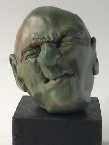 Figurative ceramic head sculpture by Rob Lansman with expressive facial features and a textured green patina.