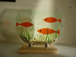 Fused glass artwork with three orange fish and aquatic plants by Roger Sturley, HART guest artist.